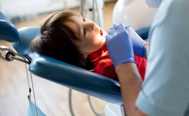 Ilustrasi gambar seorang dokter gigi sedang memeriksa masalah gigi yang terjadi pada anak