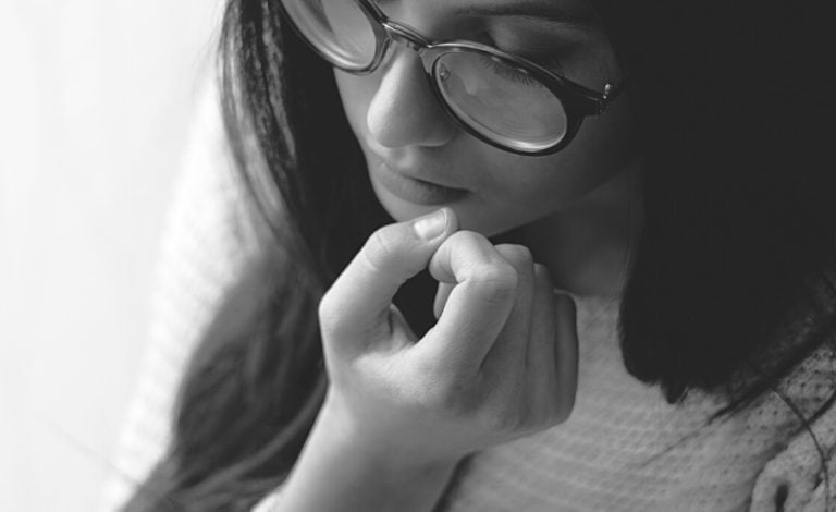 Seorang perempuan sedang gigit kuku jari dengan giginya