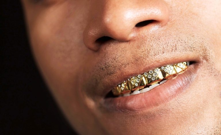 Pria dengan grillz gigi yang menampilkan tren fashion hip-hop.