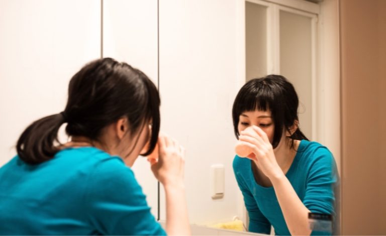 Wanita melakukan oil pulling dengan minyak kelapa untuk membersihkan mulut dan menyegarkan napas.